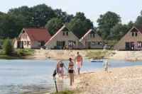 Mensen spelen bij de zwemvijver inde buurt van de bungalows